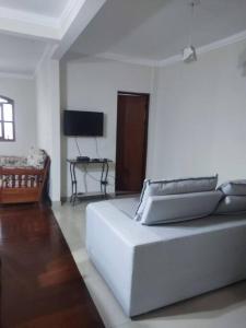 a living room with a white couch and a television at Casa rústica Jardim Abaete in Piracicaba