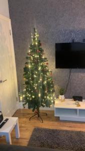 a christmas tree with lights in a living room at Homes from home by Tulloch Properties in Maidstone
