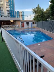 a large swimming pool with a white fence and a building at Apartamento nuevo norte Cali in Cali