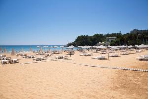 einen Sandstrand mit Sonnenschirmen und Stühlen und das Meer in der Unterkunft Art life apartment Flora в спальне нет окна in Alanya