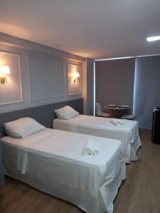 two beds in a hotel room with white sheets at Manaíra Apart Hotel - 1606 in João Pessoa