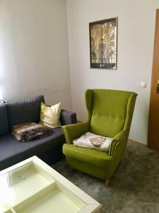 a living room with a green chair and a couch at Ferienwohnung Struth-Helmershof in Struth-Helmershof