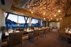 a dining room with tables and chairs and windows at Das Kohlmayr Superior in Obertauern