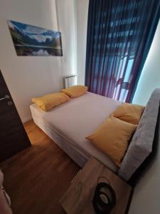 1 cama con almohadas amarillas en una habitación con ventana en Apartment Bulevar Square, en Sarajevo