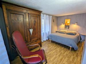a bedroom with a bed and a red chair at Gîte chaleureux en pleine nature avec terrasse, idéal pour randonnées et vététistes, proche de Gérardmer - FR-1-589-125 in Le Syndicat