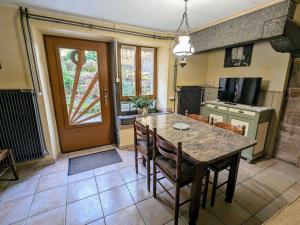 a dining room with a table and a kitchen with a door at Gîte chaleureux en pleine nature avec terrasse, idéal pour randonnées et vététistes, proche de Gérardmer - FR-1-589-125 in Le Syndicat