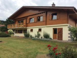 a house with a balcony and red flowers in the yard at Gîte confortable à Gérardmer avec jardin, ski, randonnées et activités nautiques - FR-1-589-128 in Gérardmer