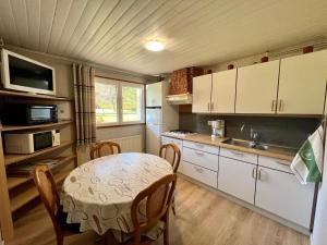 a kitchen with a table and a sink and a microwave at Gîte confortable à Gérardmer avec jardin, ski, randonnées et activités nautiques - FR-1-589-128 in Gérardmer