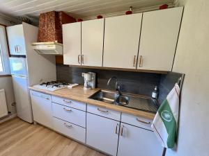 a small kitchen with white cabinets and a sink at Gîte confortable à Gérardmer avec jardin, ski, randonnées et activités nautiques - FR-1-589-128 in Gérardmer +10 photos