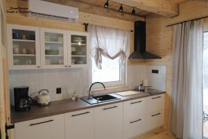 a kitchen with white cabinets and a window at SzumiPuszcza - domki z sauną lub balią in Białowieża