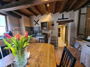 a vase of flowers on a wooden table in a kitchen at À louer : Ancienne forge avec sauna, piscine, proche plage et sites historiques - FR-1-591-193 in Le Menoux