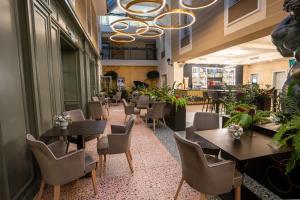 un ristorante con tavoli, sedie e piante di ATLAS Hotel a Timişoara