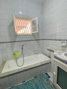 baño blanco con bañera y ventana en Omnia House en Monastir