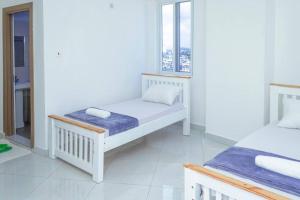 um quarto branco com 2 camas e uma janela em Angani Apartment em Mombasa