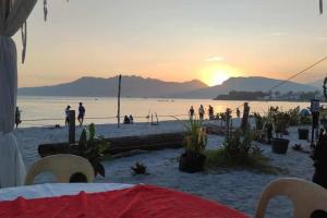 una puesta de sol en una playa con gente en el agua en Baloy beach house, en Olóngapo