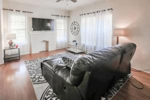 uma sala de estar com um sofá de couro e uma televisão em Trailside Retreat in the City em Tulsa