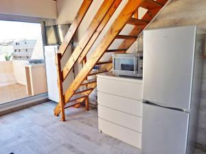 eine Küche mit einem weißen Kühlschrank und einer Treppe in der Unterkunft Appartement Marseillan-Plage, 2 pièces, 4 personnes - FR-1-387-162 in Marseillan