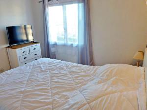 Schlafzimmer mit einem weißen Bett und einem TV in der Unterkunft Appartement Marseillan-Plage, 2 pièces, 4 personnes - FR-1-387-162 in Marseillan