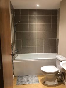 a bathroom with a tub and a toilet and a sink at GALAXY APARTMENT in Stockport
