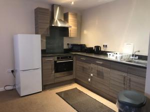 a kitchen with a white refrigerator and a sink at GALAXY APARTMENT in Stockport