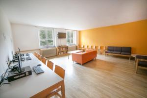 um quarto amplo com uma sala de espera com secretárias e cadeiras em Muffin Hostel em Salzburgo