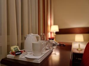 ein Tablett mit Tassen auf einem Tisch in einem Hotelzimmer in der Unterkunft Hotel Sfinksas in Kaunas