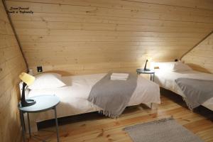 2 łóżka w pokoju z drewnianymi ścianami w obiekcie SzumiPuszcza - domki, sauna, jacuzzi w Białowieży