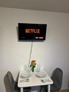 a white table with chairs and a tv on the wall at Modern Apartment in Gütersloh Avenwedde in Gütersloh