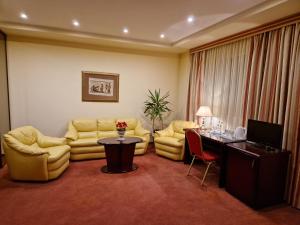 uma sala de estar com um sofá, uma mesa e cadeiras em Hotel Sfinksas em Kaunas