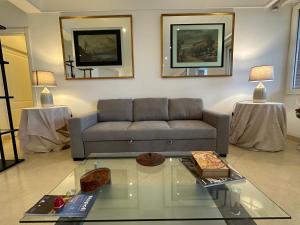 ein Wohnzimmer mit einem Sofa und einem Glastisch in der Unterkunft Luxury Posillipo Capri View Apartment in Neapel