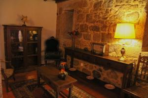 a living room with a fireplace and a table with a lamp at Casa d'Acha in São Miguel de Acha