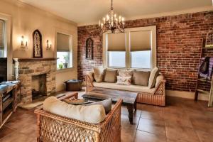 een woonkamer met een bank en een bakstenen muur bij The Teak Follow, beautiful brick enclosed space in Tulsa