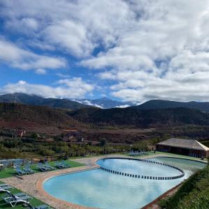 a swimming pool with chairs and mountains in the background at Panorama Complex in Tahannout