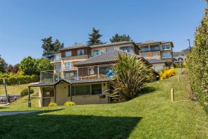 una casa grande en una colina con un patio verde en Hermoso departamento frente al lago con piscina en San Carlos de Bariloche