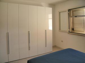 1 dormitorio con armarios blancos y ventana en Villa Giulia Salento Mare, en Torre Vado