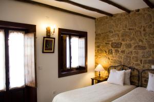 1 dormitorio con 2 camas y pared de piedra en Casa d'Acha, en São Miguel de Acha