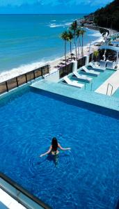 een vrouw die zwemt in een zwembad naast een strand bij Hotel Cabo Branco Atlântico in João Pessoa
