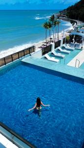 une femme se baignant dans une piscine à côté d'une plage dans l'établissement Hotel Cabo Branco Atlântico, à João Pessoa