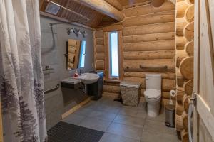 y baño con aseo y lavamanos. en Les Chalets Tourisma - Chalet en bois rond avec spa et lac privé - Le Caribou en Sainte-Catherine