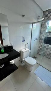 a bathroom with a toilet and a glass shower at POUSADA RECANTO DAS VERTENTES in Capitólio