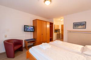 a bedroom with two beds and a chair and a television at Aschau-Apartments in Aschau im Chiemgau