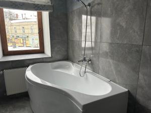 eine weiße Badewanne im Bad mit Fenster in der Unterkunft Centralnyi hotel in Poltawa