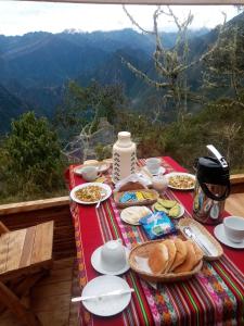 a table with plates of food on top of a mountain at Refugios Salkantay - "StaySoraypampa - Accommodation near Humantay Lake and Salkantay Trek" in Cusco