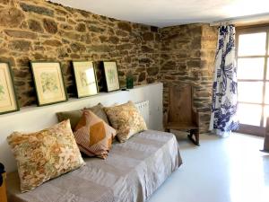 1 dormitorio con cama con almohadas y pared de piedra en Casa de las Flores / Casa de campo LUGO, en A Pontenova