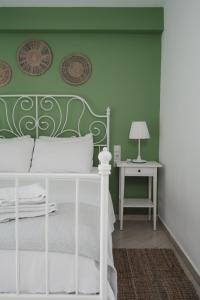 1 dormitorio con cama blanca y pared verde en K-houses P, en Lefkada
