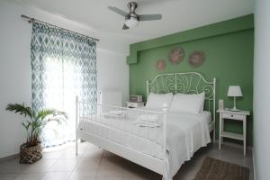 1 dormitorio con cama blanca y pared verde en K-houses P, en Lefkada