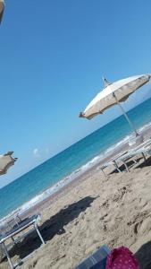 ein Strand mit Stühlen und einem Sonnenschirm und das Meer in der Unterkunft Dimora Elisabetta casa a pochi passi dal mare in Pontecagnano