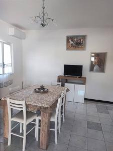 eine Küche mit einem Tisch mit Stühlen und einem TV in der Unterkunft Dimora Elisabetta casa a pochi passi dal mare in Pontecagnano