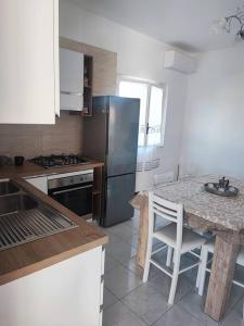 eine Küche mit einem Tisch und einem Kühlschrank aus Edelstahl in der Unterkunft Dimora Elisabetta casa a pochi passi dal mare in Pontecagnano