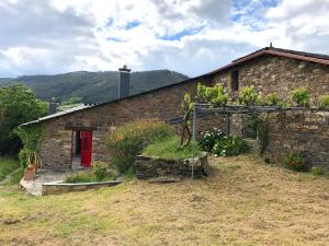 een stenen huis met een rode deur en een aantal planten bij Casa de las Flores / Casa de campo LUGO in A Pontenova